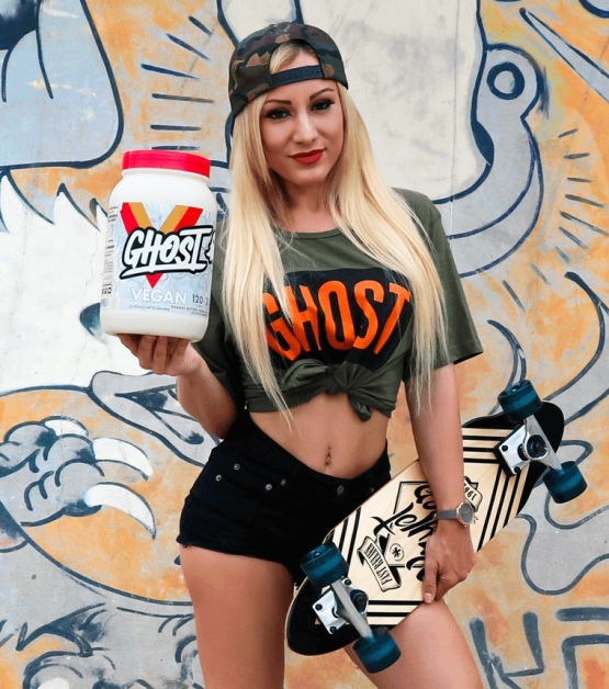sporty young woman holding a tub of ghost nutrition vegan protein